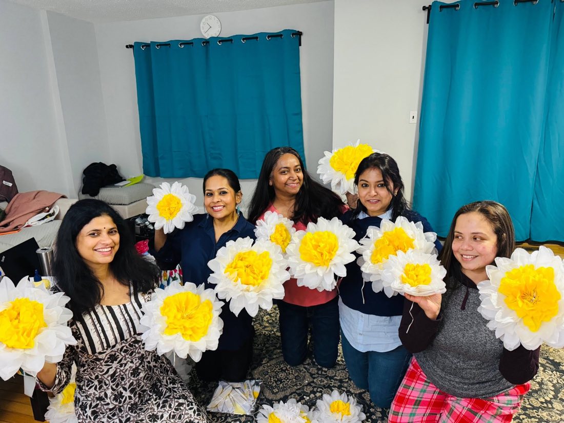 Volunteers holding handmade paper flowers used to decorate a puja stage