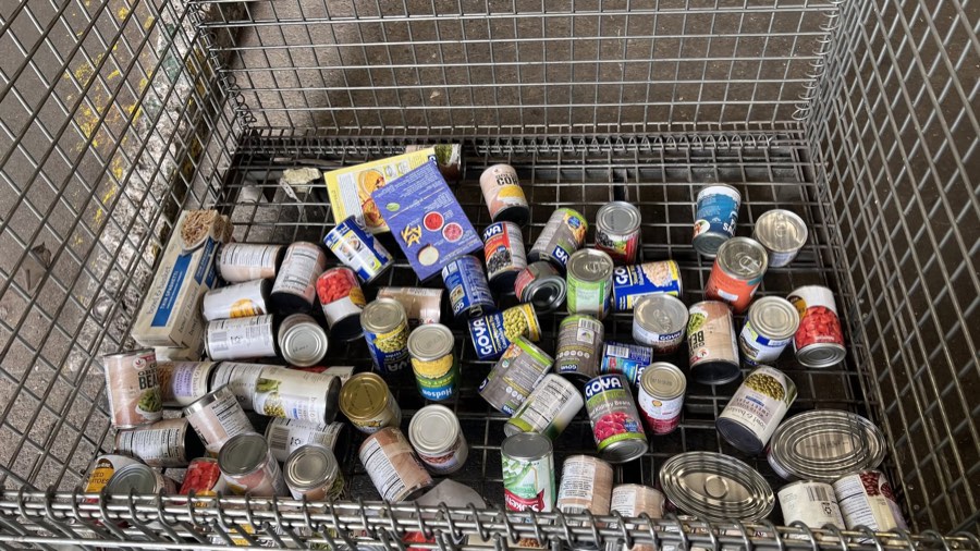Canned goods and pantry staples collected in a wire donation bin