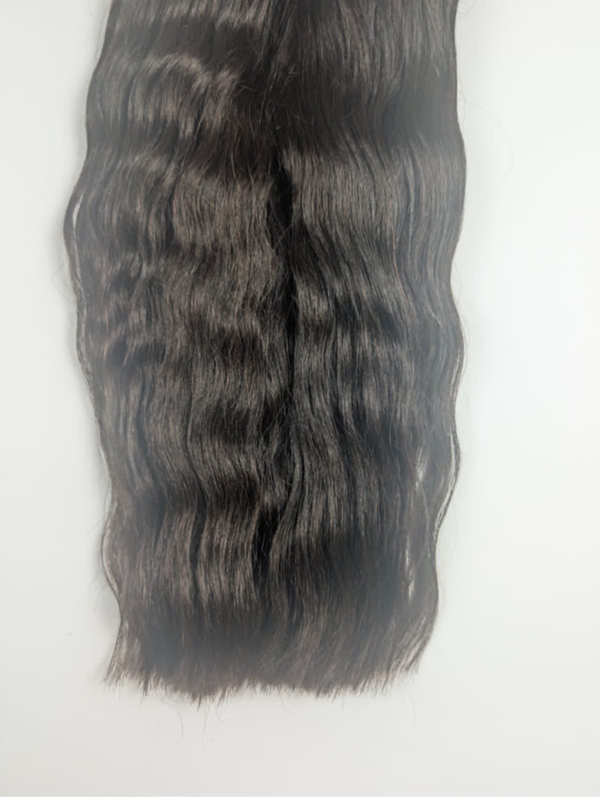 Lange, donkerbruine golvende haarweave op een lichte achtergrond.
