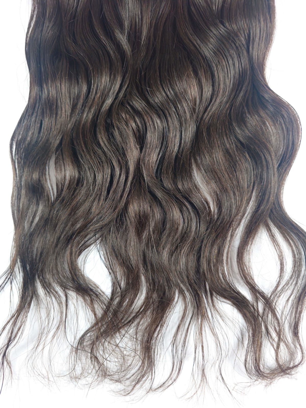 Lange gewellte braune Haare mit hellen Strähnen vor weißem Hintergrund.