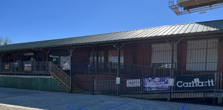 The Tom Waters store on Joor Road today: a long red building with a metal roof, raised on piers, with a Carhartt banner along the front railing.