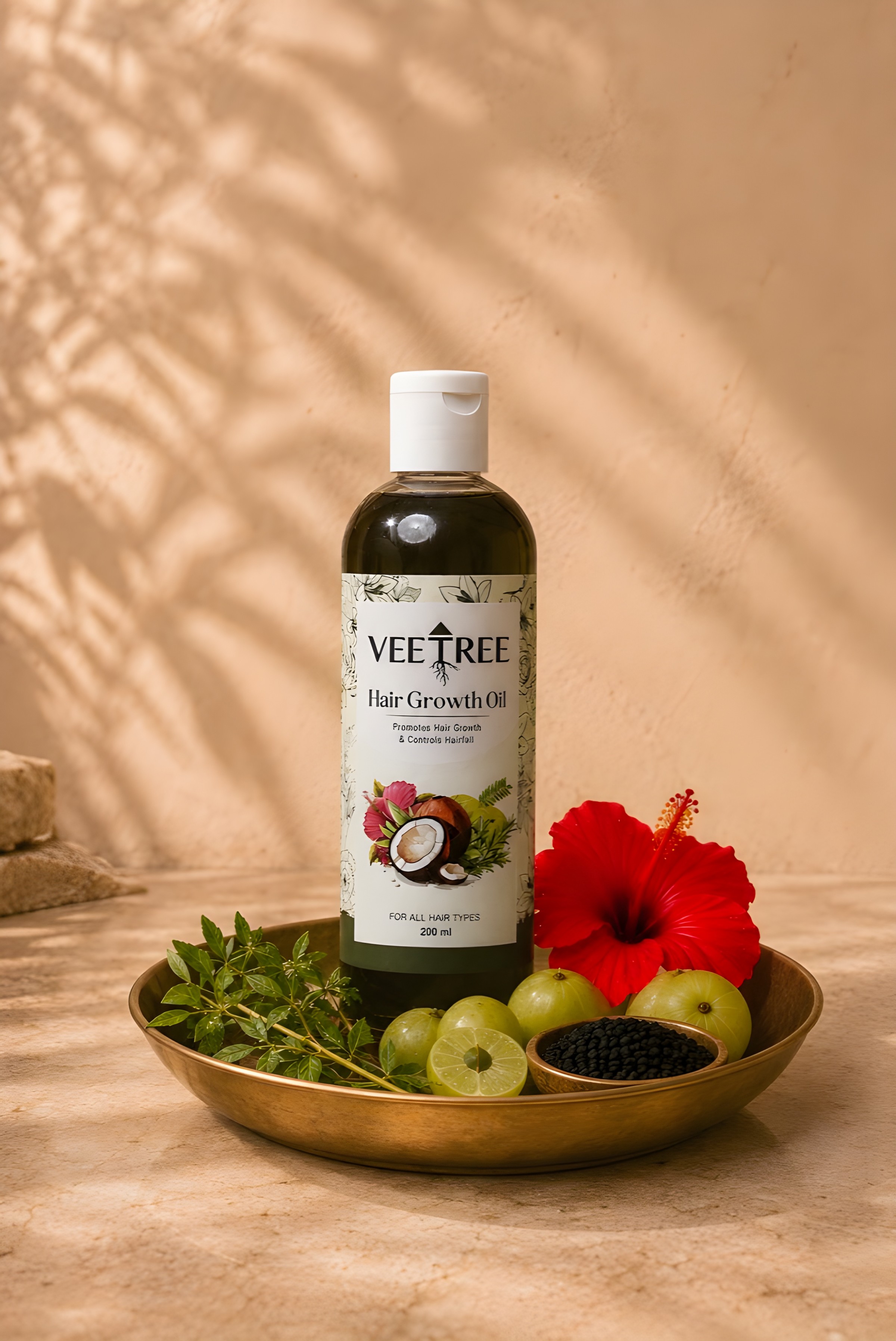 Veetree Hair Growth Oil in a bottle set in a brass plate with amla, hibiscus, curry leaves and black seeds