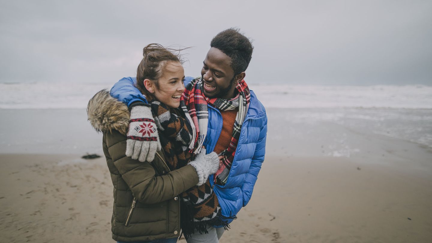 Man interested in how to prevent erectile dysfunction walking down a beach with his partner