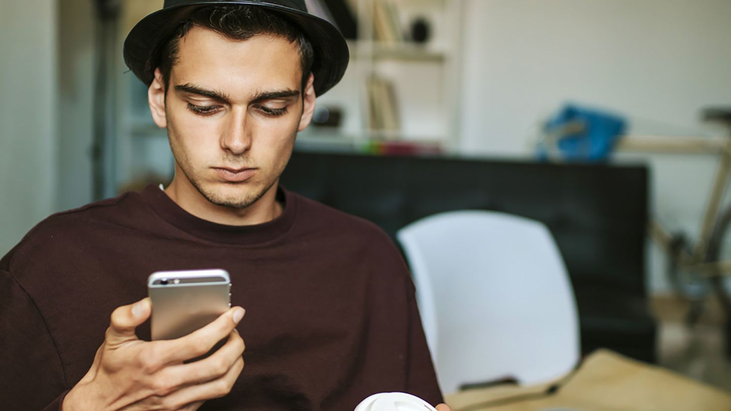 Man at home holding a coffee and checking on his phone for diabetes treatments