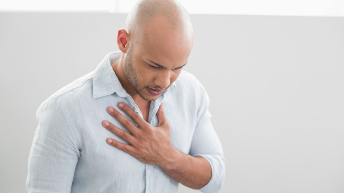 Man in shirt holding chest feels an asthma attack coming on