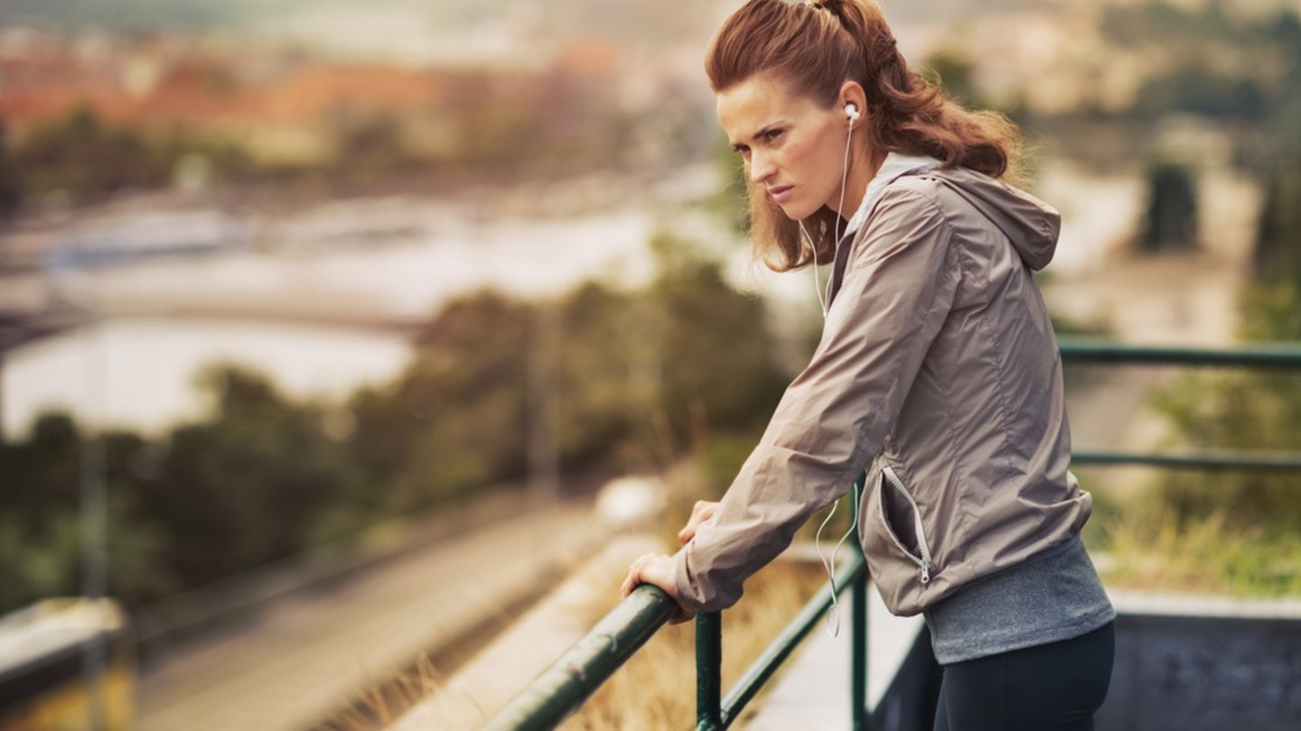 Woman who has stopped jogging leaning on railings wondering if jogging causes low blood pressure