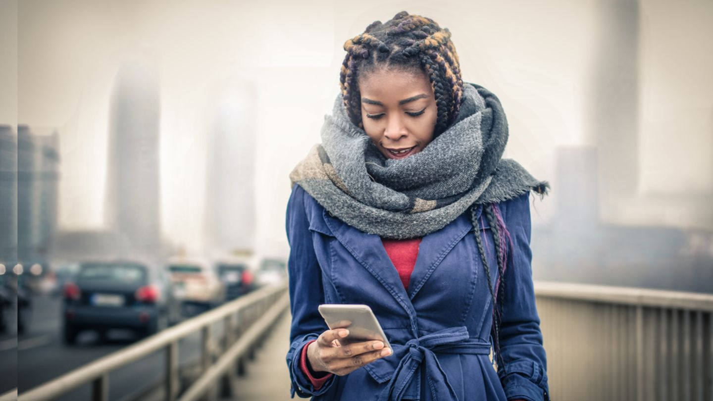Woman crossing a bridge looking up information on the pill and periods on her phone