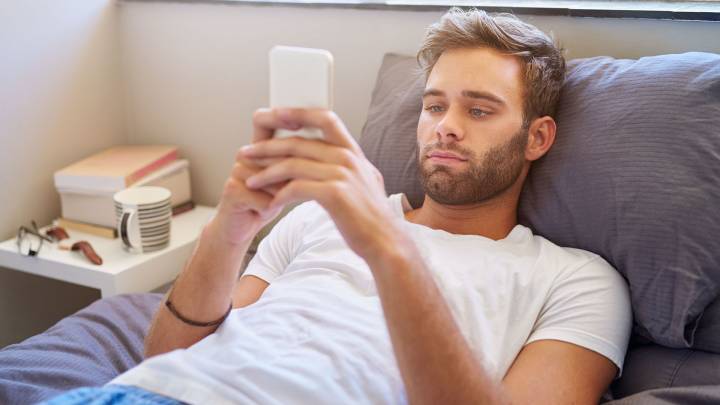 Man lying in bed checking on his phone for how quickly Viagra starts working