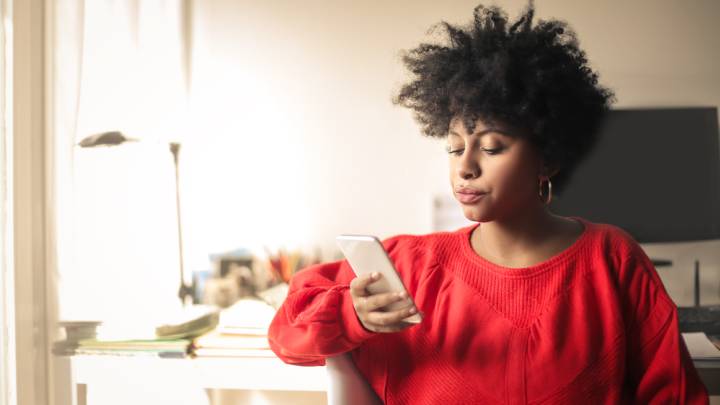 Black woman sat at home exploring the internet on her phone for types of genital warts
