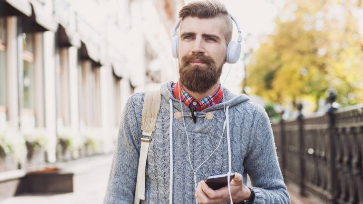 Bearded man walking with phone in hand thinking about what the symptoms of hiv in men are