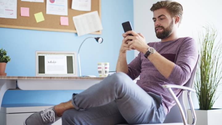 Man sat at his desk at home looking on his phone tips on combating infertility