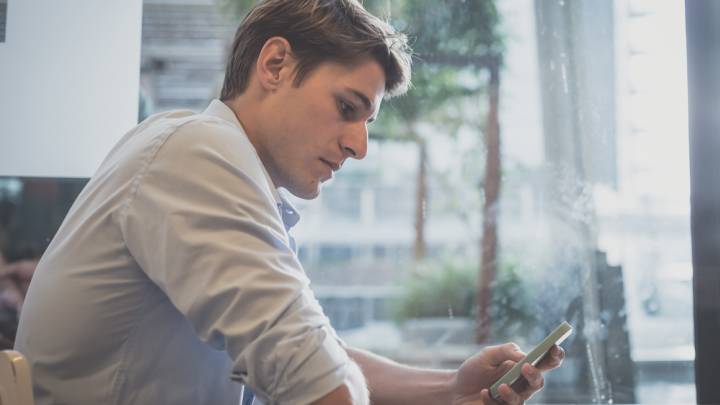Man sat at a table in front of a window researching low sex drive on his phone