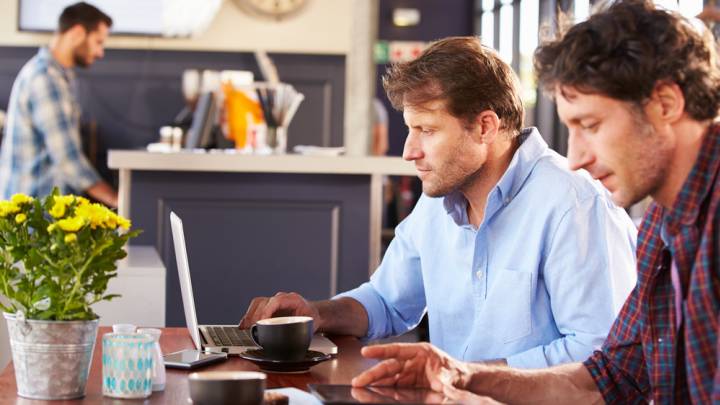 Man with friend in cafe reading about the male menopause