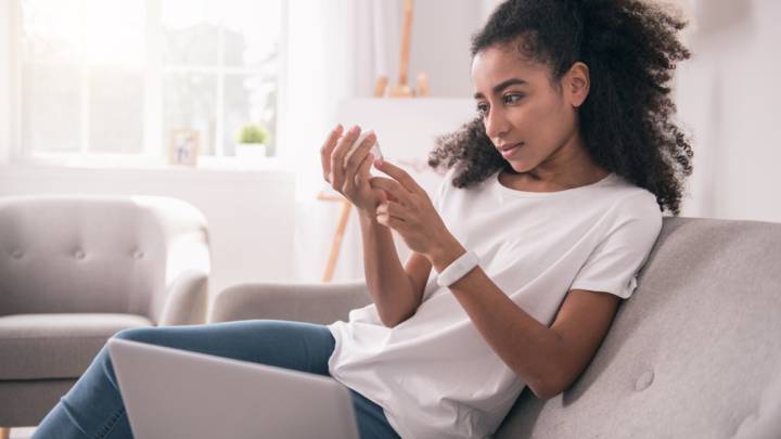 Woman examining cream next to her laptop