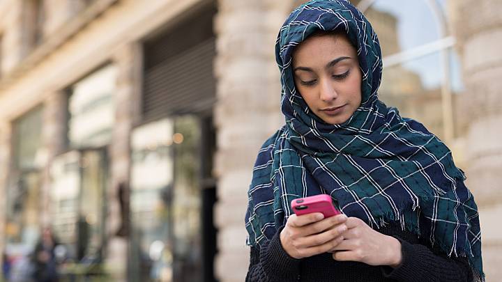 Woman stood in the street checking how effective the pill is on her phone