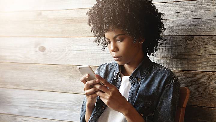 African American woman sat on chair looking on mobile for how to order a home STD test