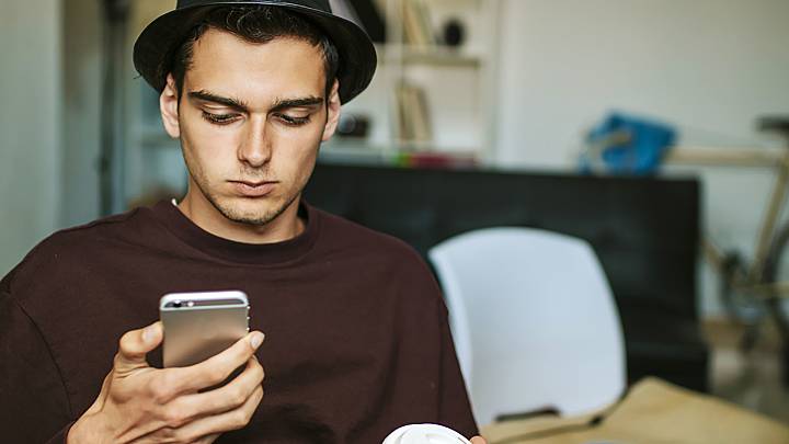 Man at home holding a coffee and checking on his phone for diabetes treatments