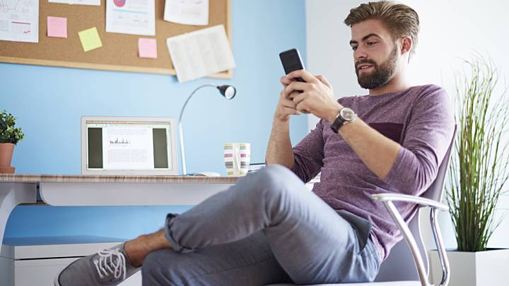 Man sat at his desk at home looking on his phone tips on combating infertility