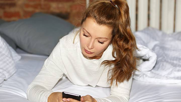Woman looking for progesterone pills on her phone in bed