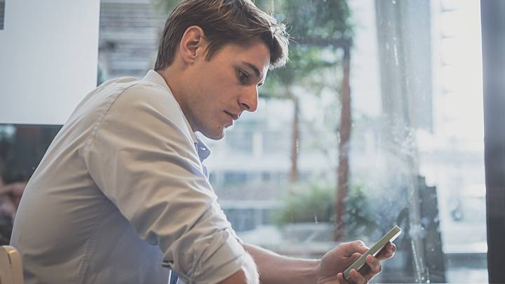 Man sat at a table in front of a window researching low sex drive on his phone