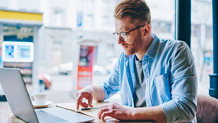 Man in cafe checking his laptop to see if there is a herpes vaccine