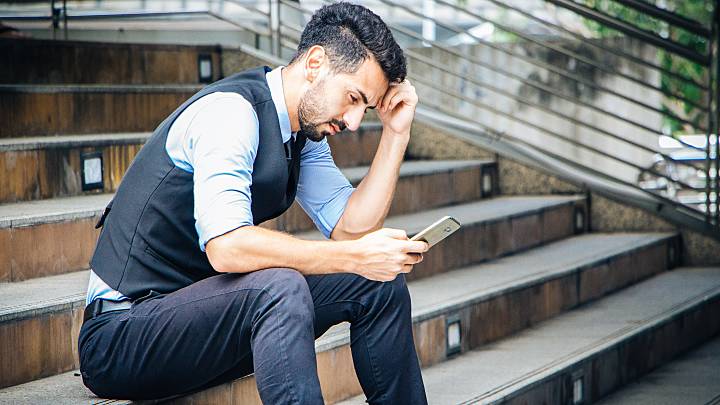 Besorgter, junger Mann informiert sich auf seinem Smartphone über Symptome und Therapien von Chlamydia trachomatis.