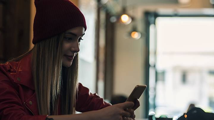 Eine junge Frau mit ihrem Smartphone in einem Cafe. Sie informiert sich über die Portiokappe, einem hormonfreien Verhütungsmittel.