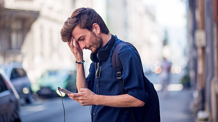 Ein junger Mann recherchiert am Handy, wie er sein Cholesterin senken kann.