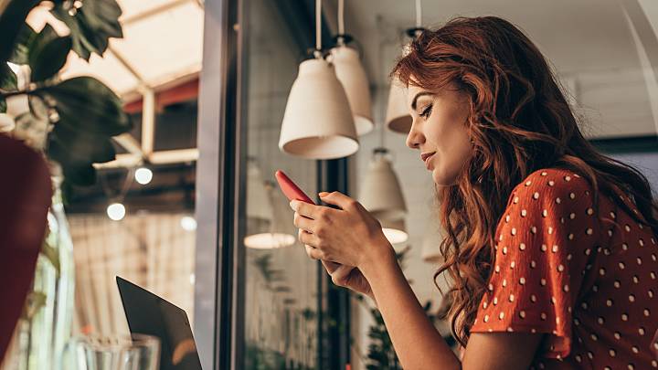 Eine junge Frau sitzt an ihrem Smartphone. Sie versucht sich über die Risiken der Pille zu informieren.