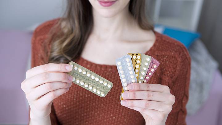 Junge Frau mit verschiedenen Pillenblistern in ihrer Hand.