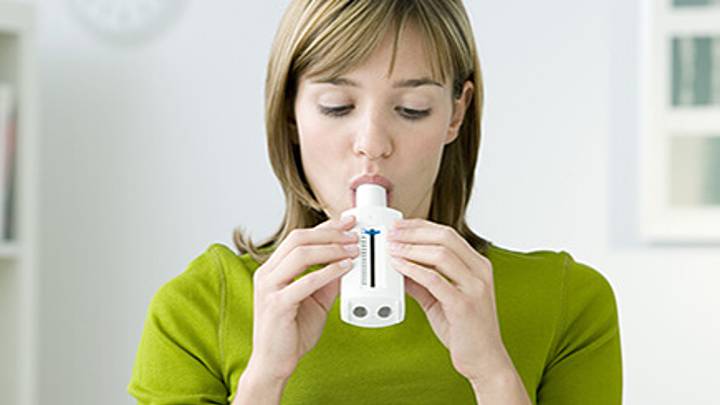 A woman using a peak flow meter