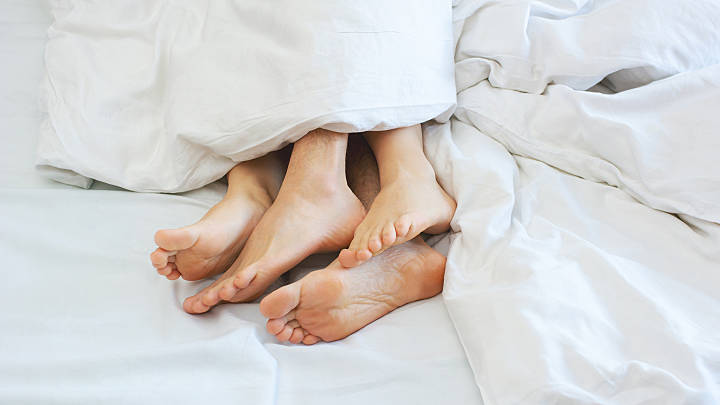 Two pairs of feet coming out of the bottom of a duvet.