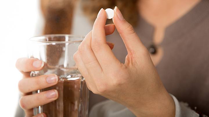 woman takes the plan b pill with a glass of water