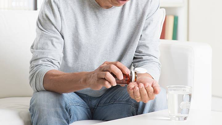 Mann schüttet eine Kapsel des Nahrungsergänzungsmittel C+ aus einer Dose.