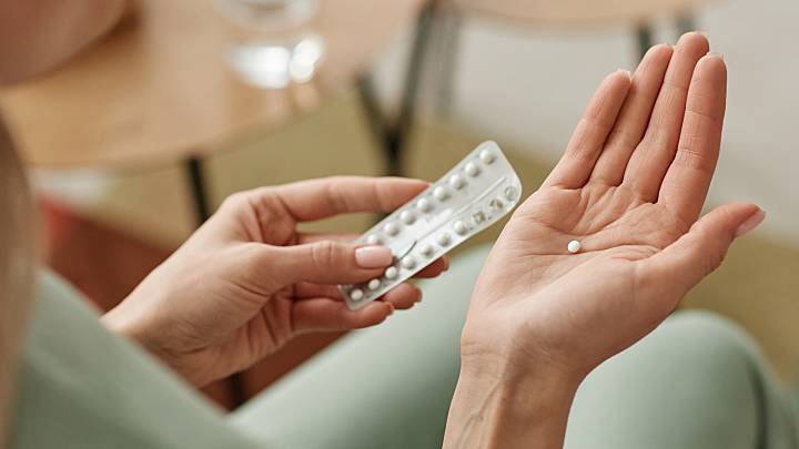 A hand holding a single pill and in the other it is a pill packet