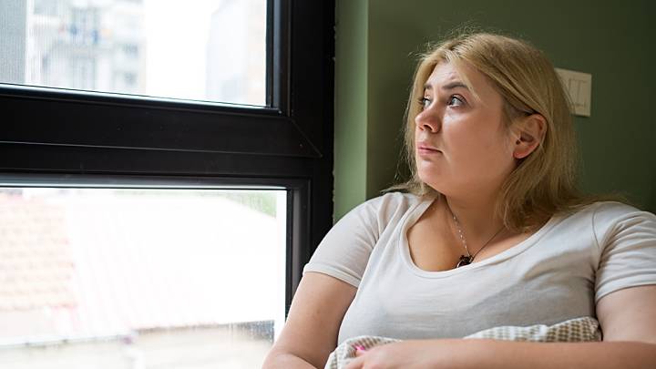 Eine Frau hat Food Noise und schaut deswegen nachdenklich aus dem Fenster