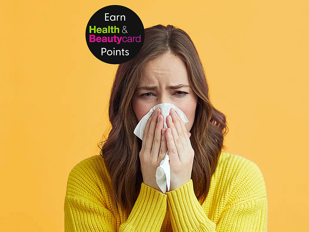 A woman sneezes into a tissue requires hay fever treatment for her symptoms