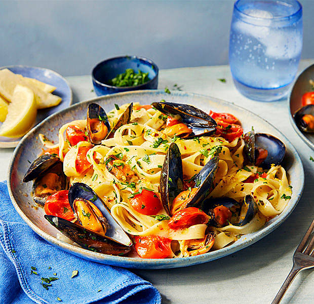 Plate of garlic mussel tagliatelle with roasted tomatoes and herbs