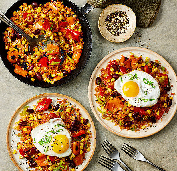 wok with piri piri pepper rice, served on 2 plates with crispy fried eggs and a side of crushed peppercorns