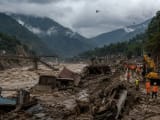 নেপালের নুওয়াকোট জেলায় ফ্ল্যাশ ফ্লাডের পর কাদা ও ধ্বংসস্তূপ পরিষ্কারের কাজ। নদীর ধারে ডুবে যাওয়া বাড়ি ও গাড়ি দৃশ্যমান।
