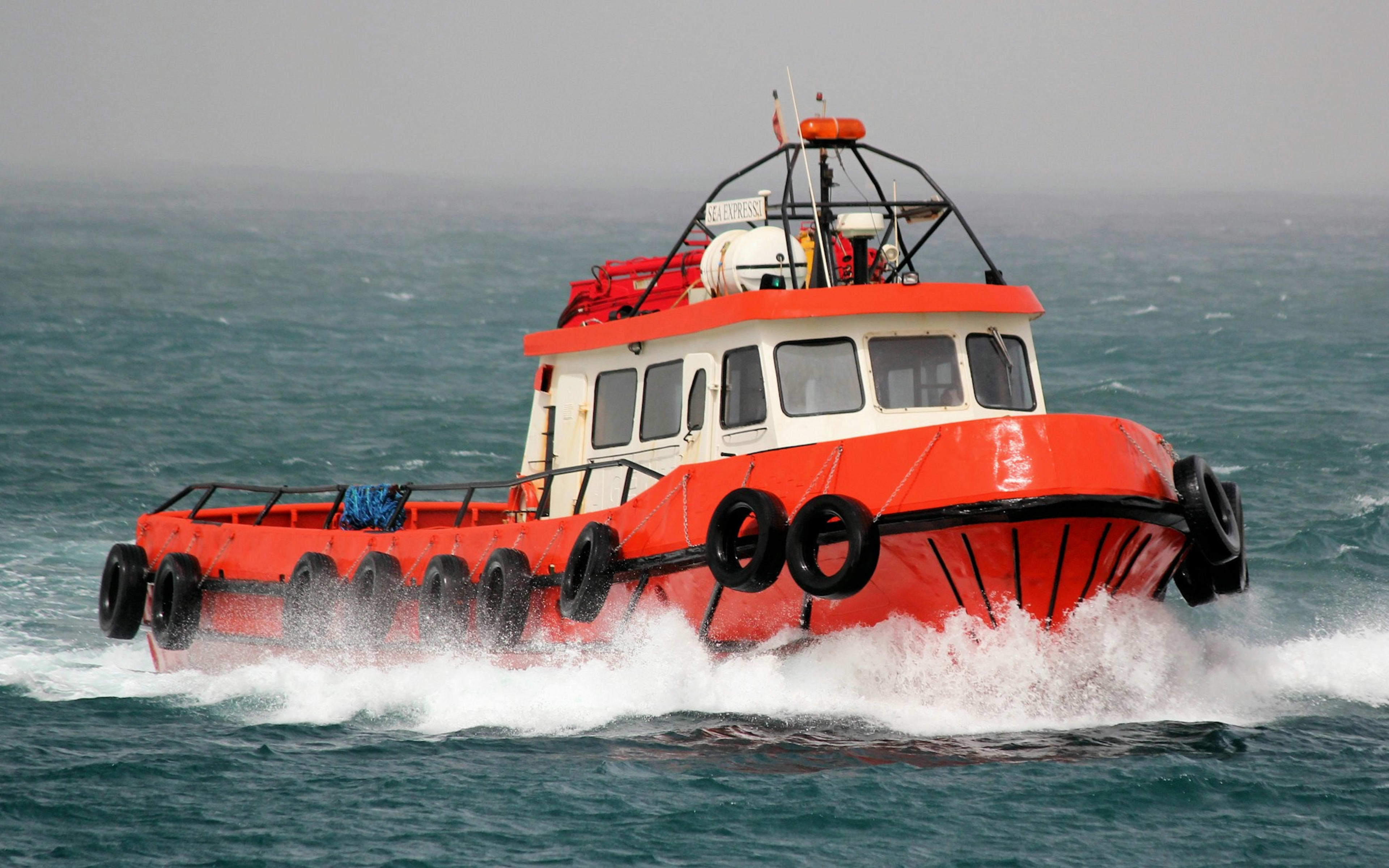 Sample photo of an orange crew boat under way in rough water
