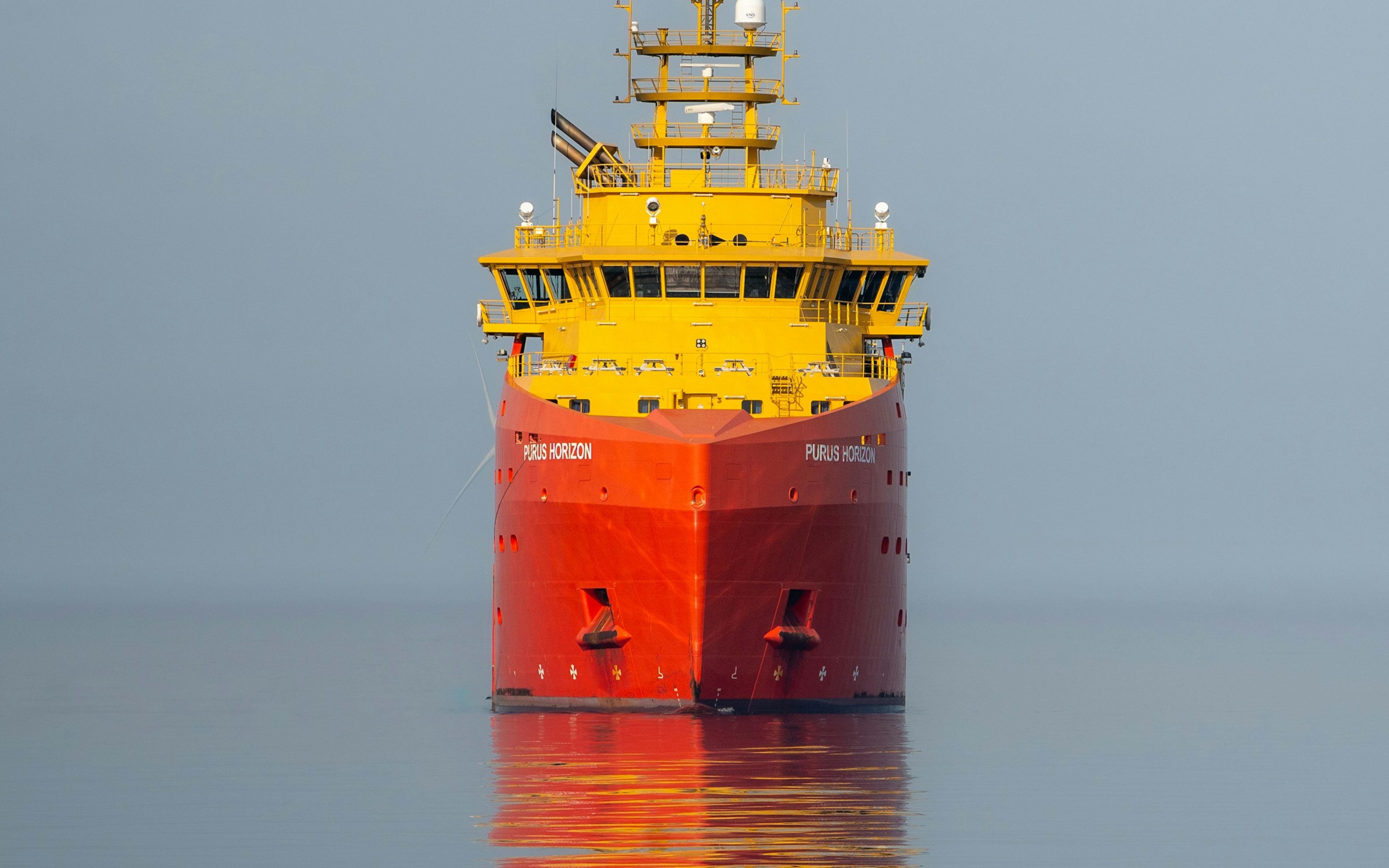 Sample photo of a red and yellow offshore supply vessel on calm water