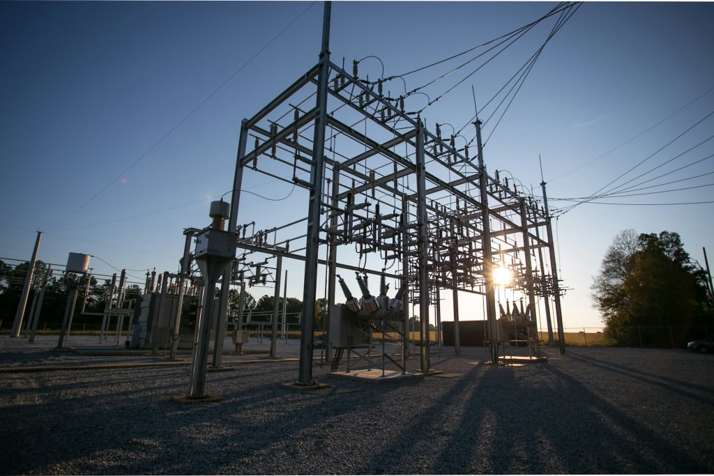 A high-voltage substation switchyard with steel gantries, busbars, disconnectors and surge arresters.