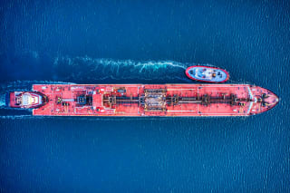 An aerial view of a red oil tanker at anchor in harbour waters.