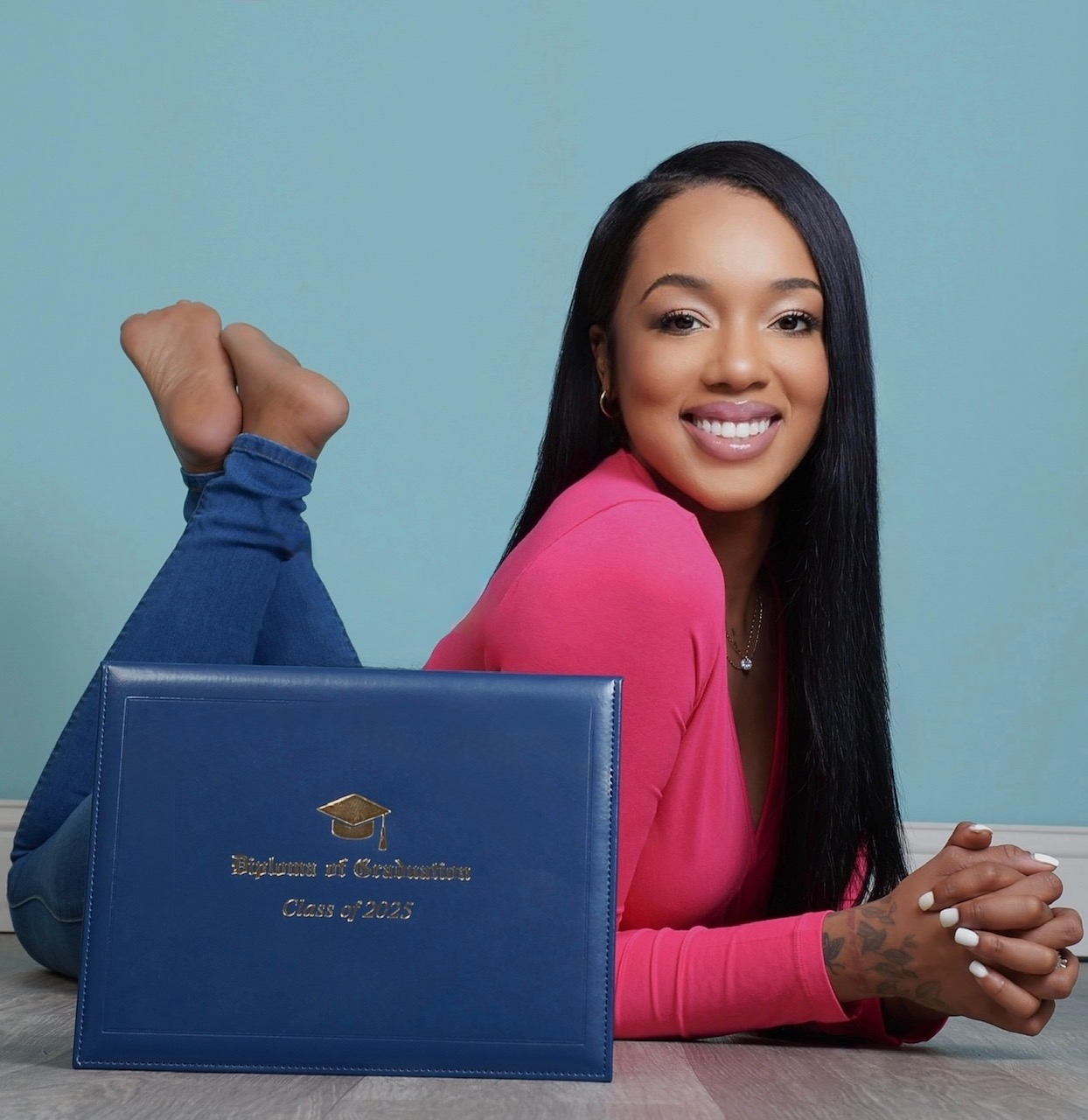 woman poses with her diploma against a blue background