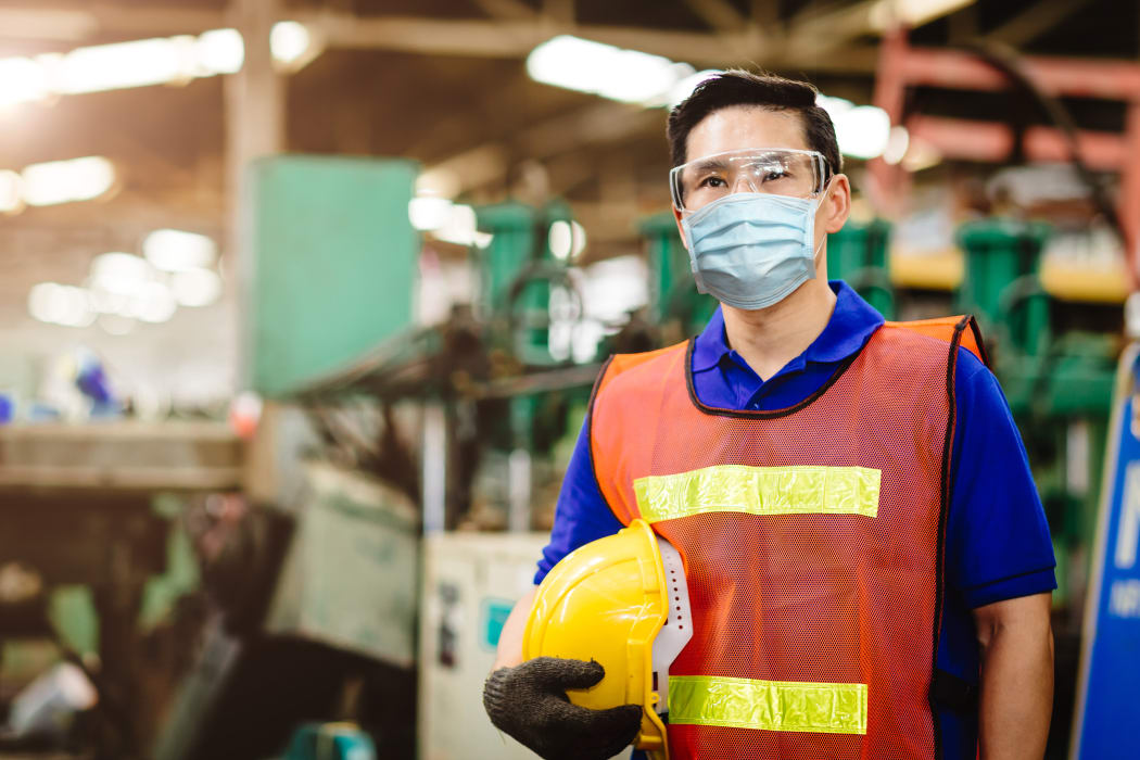 masked man holding hardhat