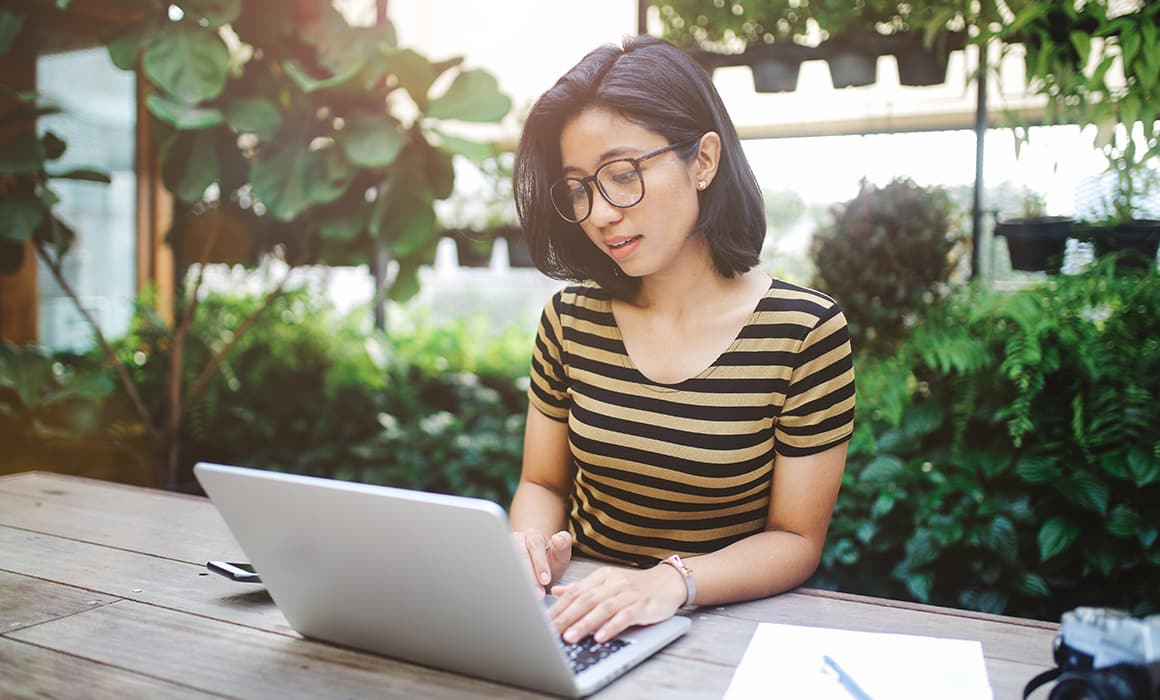 young woman with glasses working on her laptop.