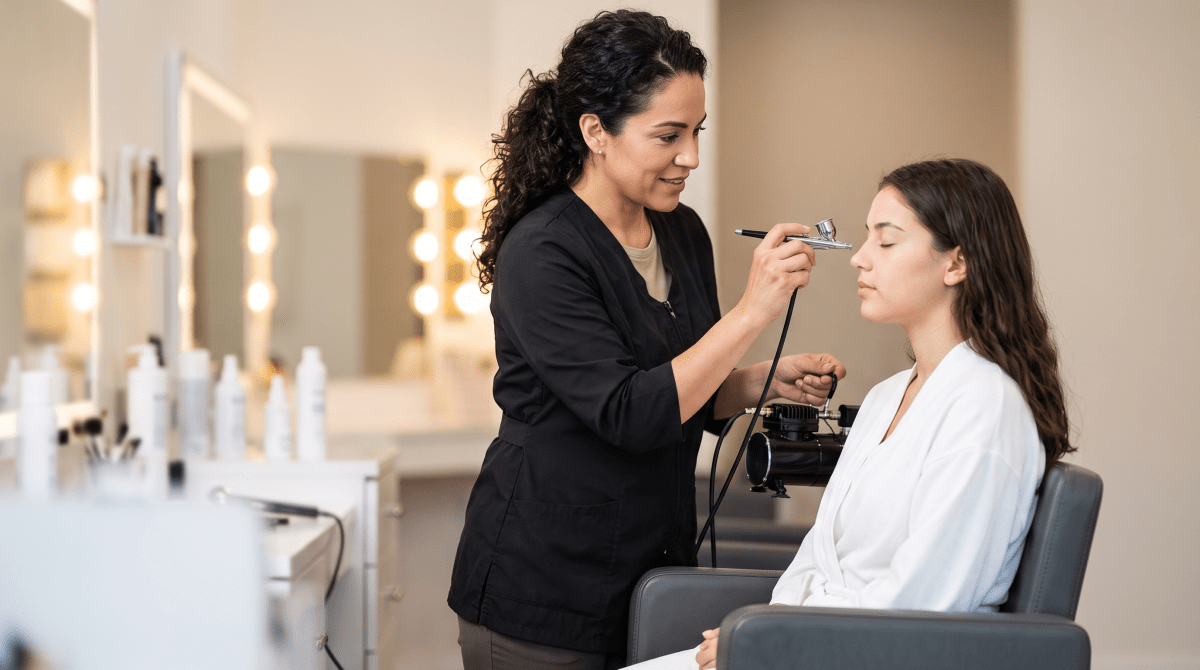 Airbrush makeup artist applying a flawless finish to a client
