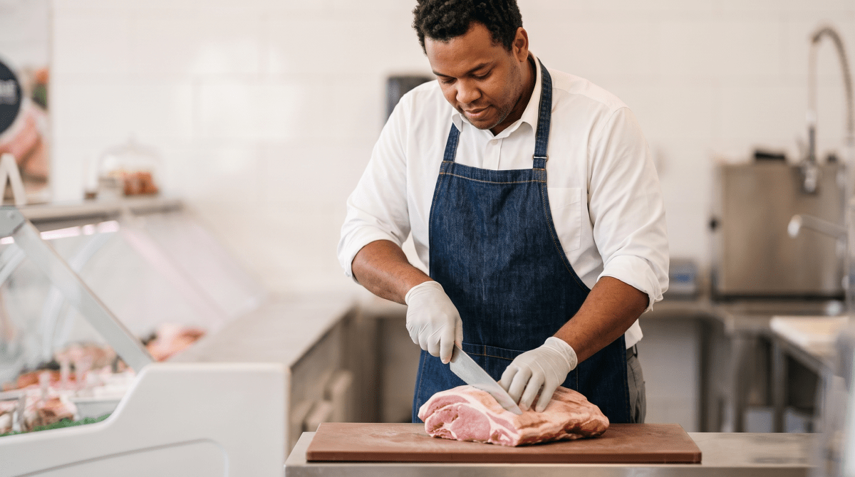 Butcher shop owner cutting meat at a butcher shop