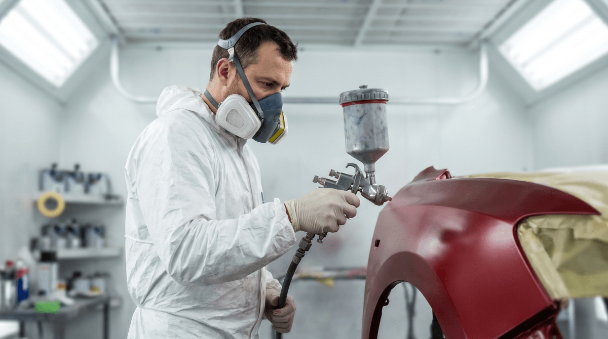 Spray-painting a vehicle in a booth at a custom auto paint shop